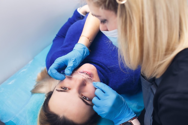 Una mujer se somete a un procedimiento de maquillaje de labios permanente en un salón de tatuajes