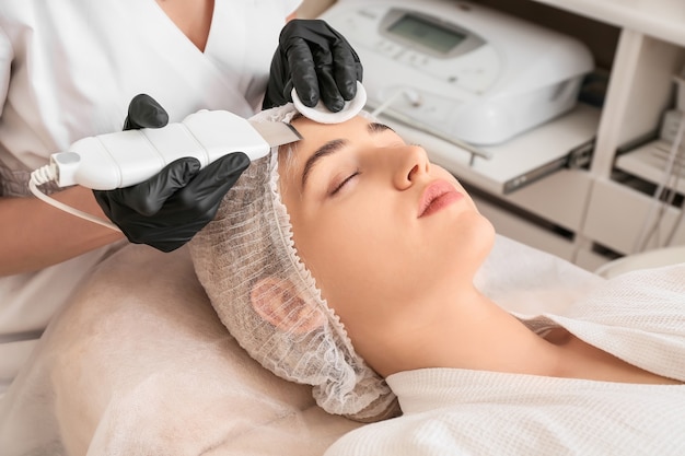 Mujer sometida a procedimiento de peeling facial en salón de belleza