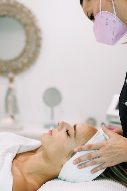 Foto mujer sometida a tratamiento con suero facial en salón de belleza.