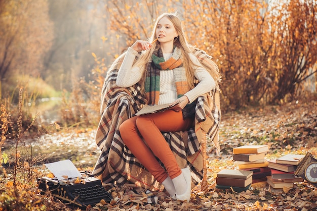 Mujer soñadora escribiendo en el parque otoño