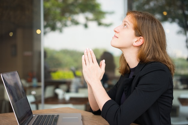 Mujer soñadora mirando hacia arriba con gesto de oración