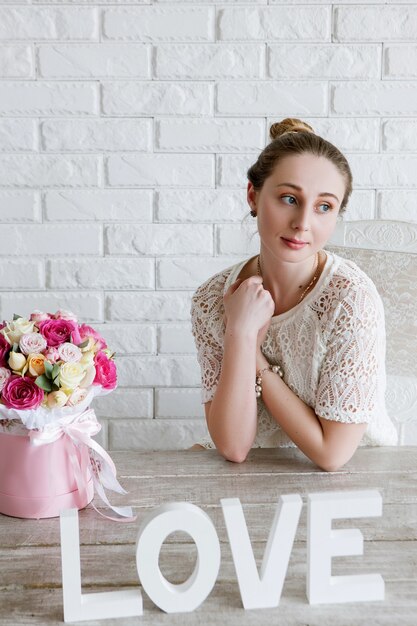 Mujer soñando despierto con regalo de flores. Concepto de amor. Ramo de rosas de colores boxeo en caja rosa en forma de cilindro. Hermoso y sensual presente para el 8 de marzo, día de San Valentín