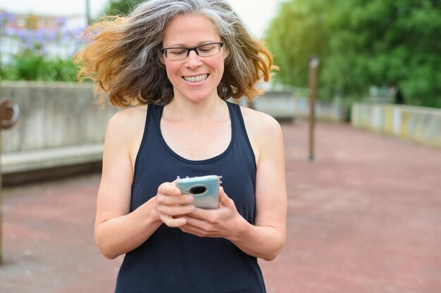 Foto la mujer sonríe al ver su actividad deportiva en su teléfono inteligente