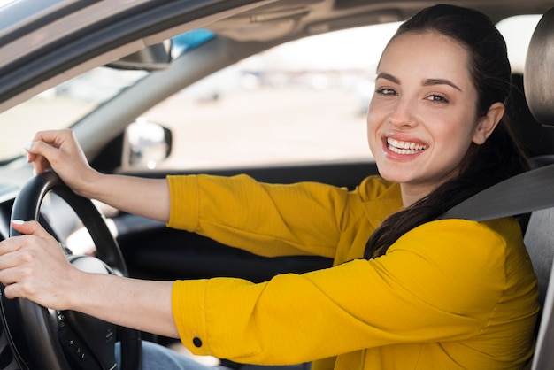 Foto mujer sonríe y sentada en el auto