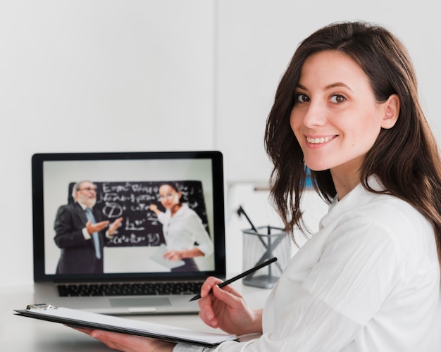 Foto mujer sonriendo y aprendiendo en línea desde la computadora portátil