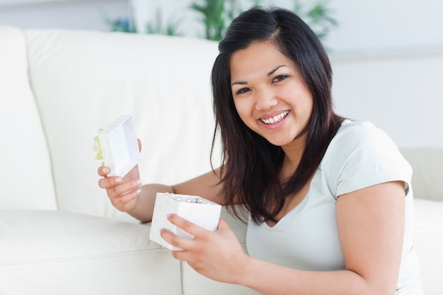 Mujer sonriendo con una caja de regalo abierta en sus manos