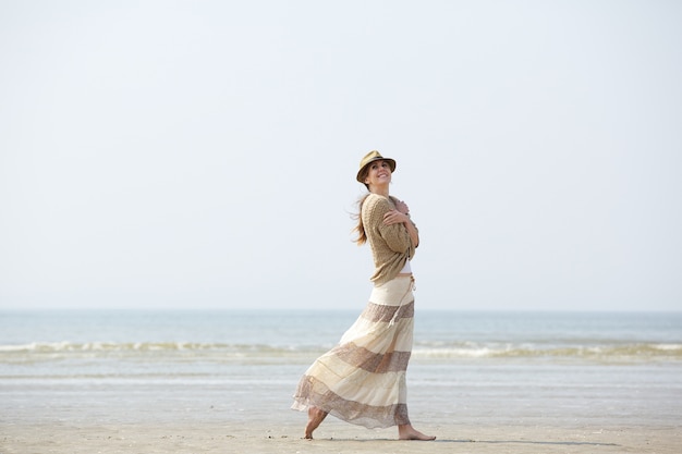 Mujer sonriendo y caminando en la playa