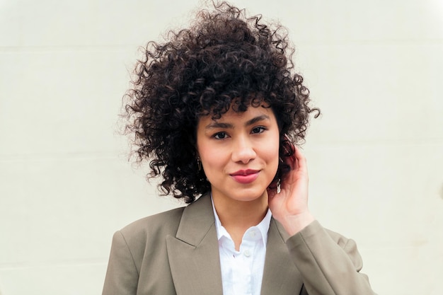 Mujer sonriendo feliz tocando su cabello rizado