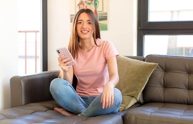 mujer sonriendo felizmente con una mano en la cadera y actitud confiada, positiva, orgullosa y amistosa