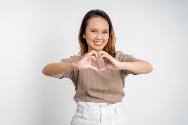 Mujer sonriendo en forma de corazón con los dedos en aislado