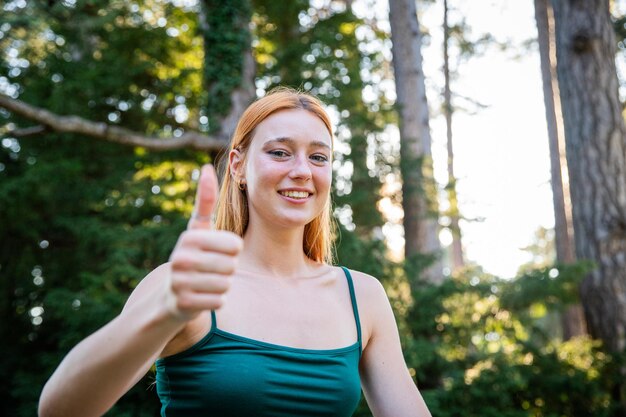 Foto una mujer está sonriendo y levantando el pulgar mientras se entrena en un parque público