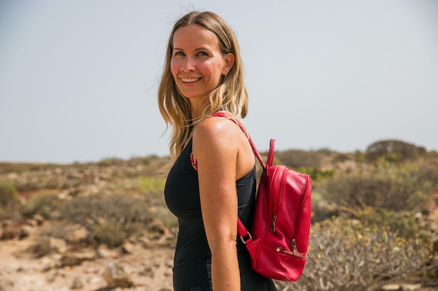 Foto una mujer está sonriendo y llevando una mochila roja en la naturaleza