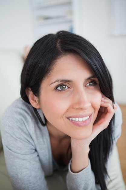 Mujer sonriendo mientras sostiene la cabeza con la palma