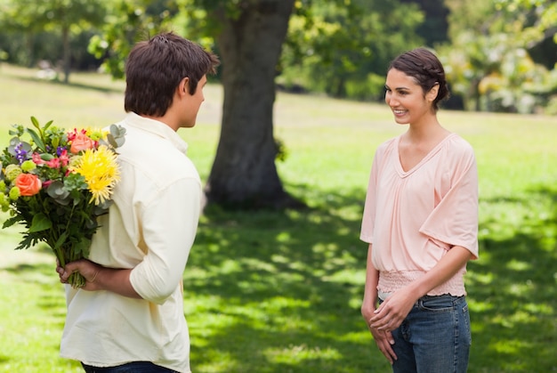 Mujer sonriendo mientras su amiga se acerca a ella con flores