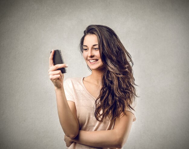 Mujer sonriendo y mirando a su teléfono inteligente