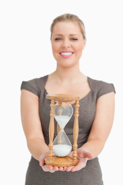 Mujer sonriendo mostrando un reloj de arena