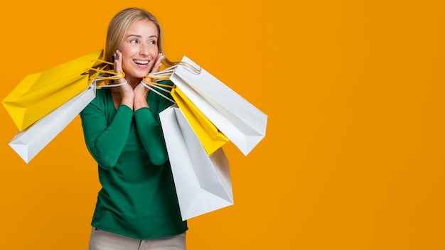 Foto mujer sonriendo y posando con muchas bolsas de la compra.