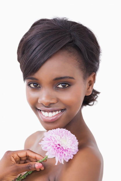 Mujer sonriendo y sosteniendo una flor de color rosa