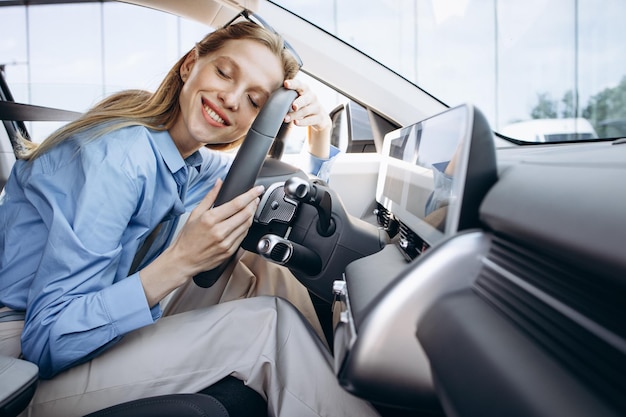 Mujer sonriendo y sosteniendo el volante en su coche eléctrico