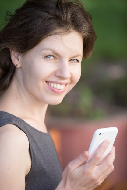 Mujer sonriendo con un teléfono inteligente