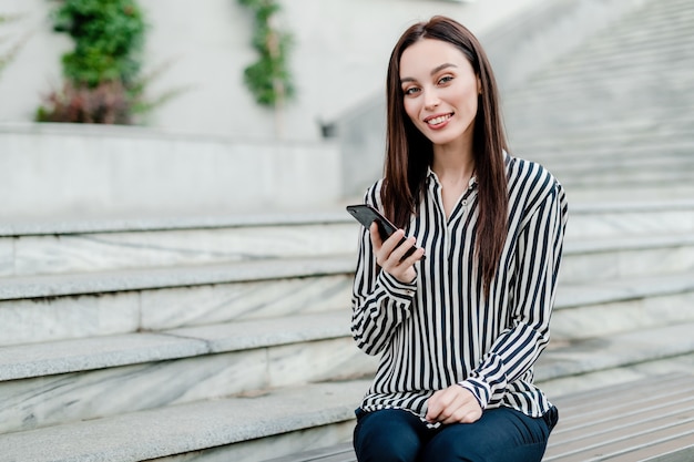 Mujer sonriendo con teléfono en mano