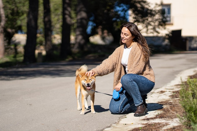 Mujer sonriente acariciando a un perro shiba inu