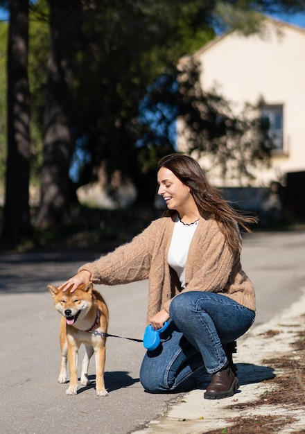 Mujer sonriente acariciando a un perro shiba inu