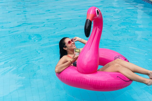 mujer sonriente, acostado, en, un, flamingo, piscina, flotador