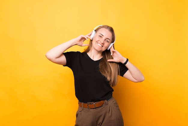 Mujer sonriente adulta lleva unos auriculares y escucha música o audiolibros.