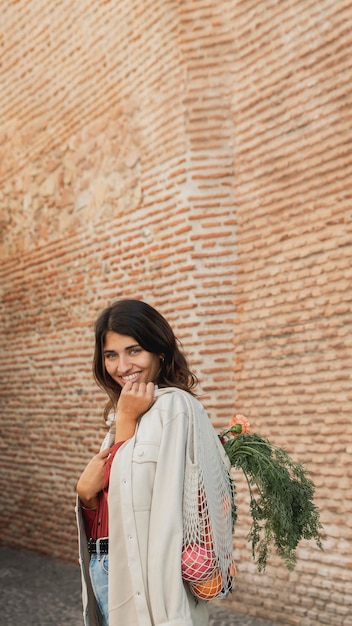 Mujer sonriente al aire libre con bolsas de la compra y espacio de copia