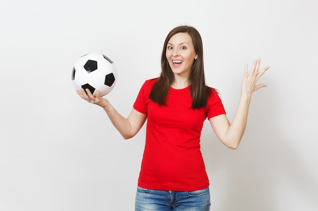 Mujer sonriente alegre joven europea atractiva, fanático del fútbol o jugador en uniforme rojo que sostiene el balón de fútbol aislado en el fondo blanco. Deporte, jugar al fútbol, animar, concepto de estilo de vida saludable.