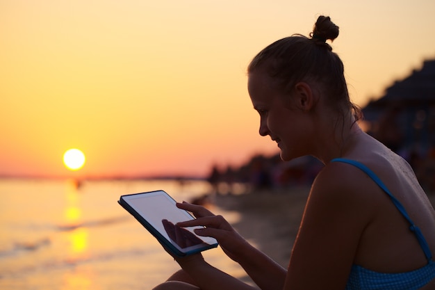 Mujer sonriente con almohadilla en la playa al atardecer