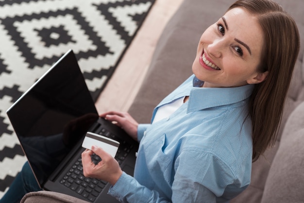 Mujer sonriente de alta vista usando su computadora portátil para comprar productos en línea