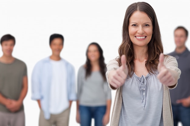 Mujer sonriente con amigos detrás de ella dando pulgares arriba