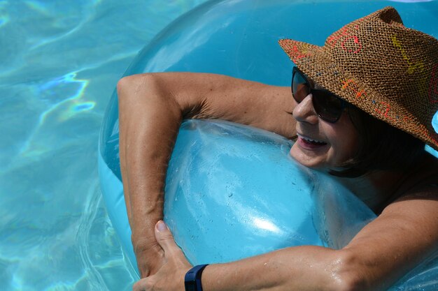 Mujer sonriente con anillo inflable nadando en la piscina