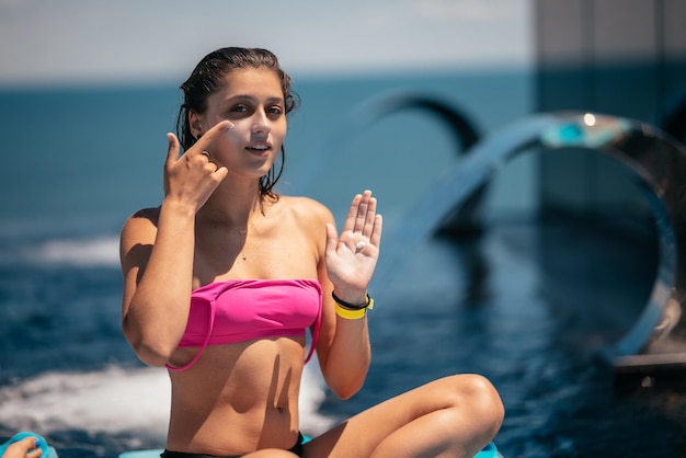 La mujer sonriente se está aplicando protector solar en la cara