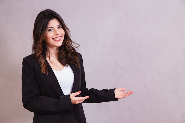 Mujer sonriente apuntando hacia el lado con espacio libre para texto.