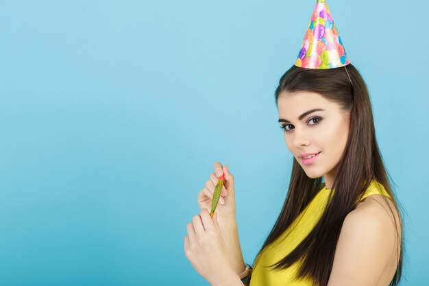 Mujer sonriente atractiva joven con un sombrero de cumpleaños