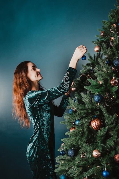 Mujer sonriente atractiva que adorna el árbol de navidad