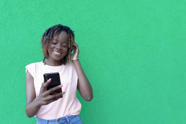 Una mujer sonriente con auriculares escucha música con un teléfono en las manos Copiar espacio