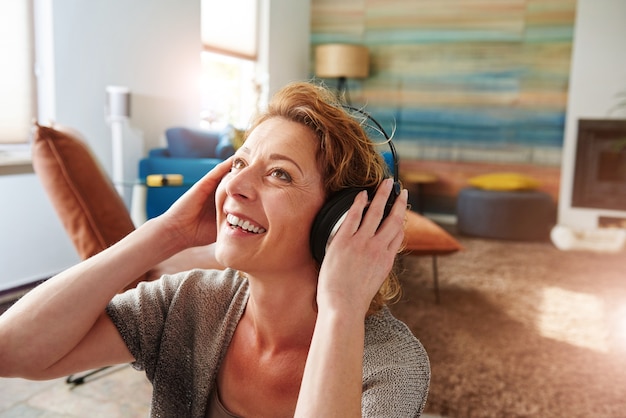 Foto mujer sonriente con auriculares y escuchando música