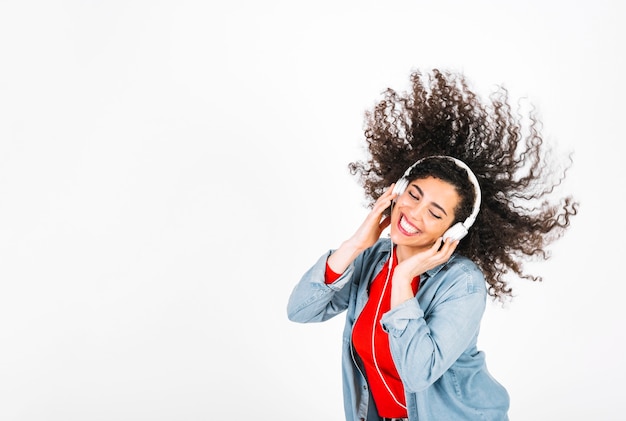 Mujer sonriente en auriculares sacudiendo el pelo