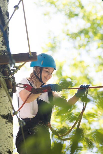 La mujer sonriente de la aventura de la cuerda camina en el puente colgante de la cuerda