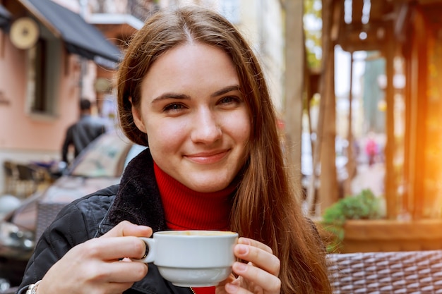 Mujer sonriente bebiendo café en la cafetería de la calle