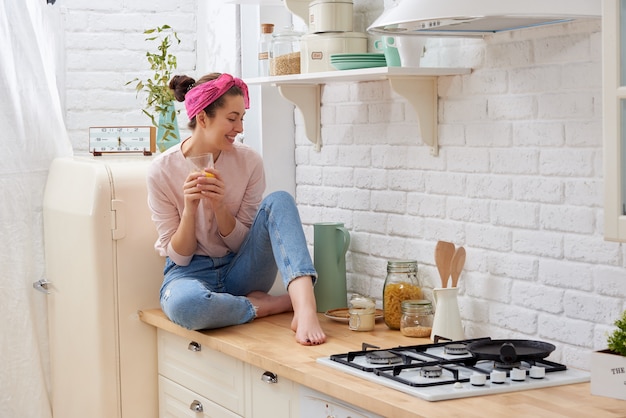 Foto mujer sonriente bebiendo jugo de naranja en la cocina