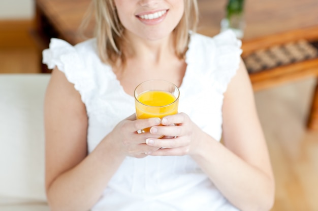 Mujer sonriente bebiendo un zumo de naranja