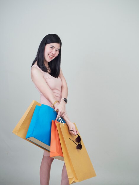 Mujer sonriente de la belleza que sostiene bolsos de compras coloridos