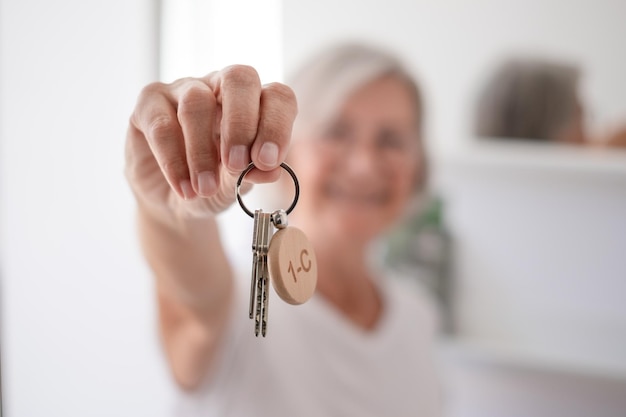 Mujer sonriente borrosa sosteniendo las llaves de la casa Casa del sueño feliz ganador comprador inquilino inquilino de la nueva casa