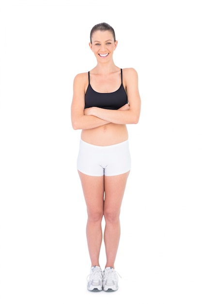 Foto mujer sonriente en brazos de travesía de ropa deportiva mirando a cámara