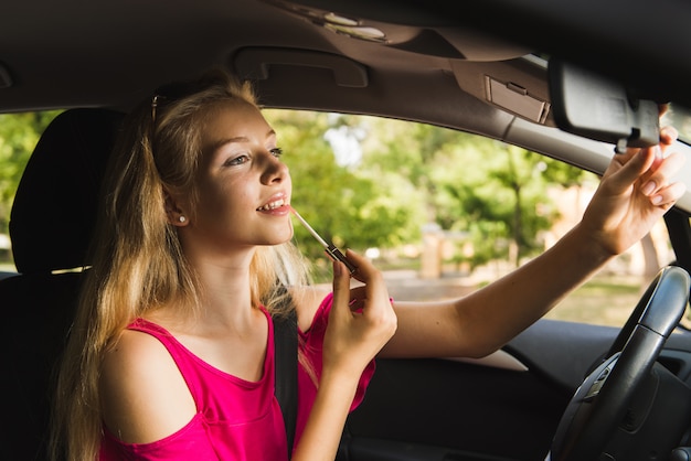 Mujer sonriente con brillo de labios en coche